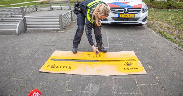 Politie Zwolle pakt de spuitbus en kalkt de boodschap op het asfalt: 1,5 meter afstand graag!.