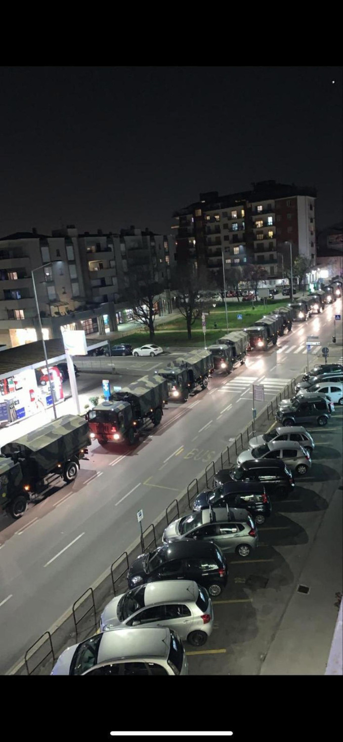 Legertrucks rijden tientallen lijkkisten met corona-slachtoffers de stad Bergamo uit.
