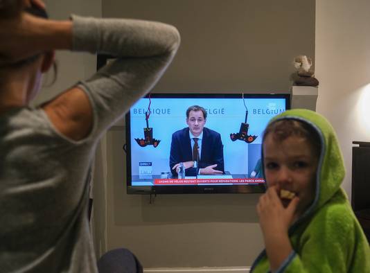 Een Belgisch gezin luistert naar premier Alexander De Croo, die een verstrengde lockdown aankondigt.