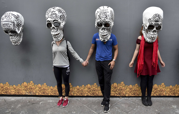 Bezoekers van een tentoonstelling poseren onder een schedel  op de avond voor viering van de Dag van de Doden in Mexico City. Foto Yuri Cortez