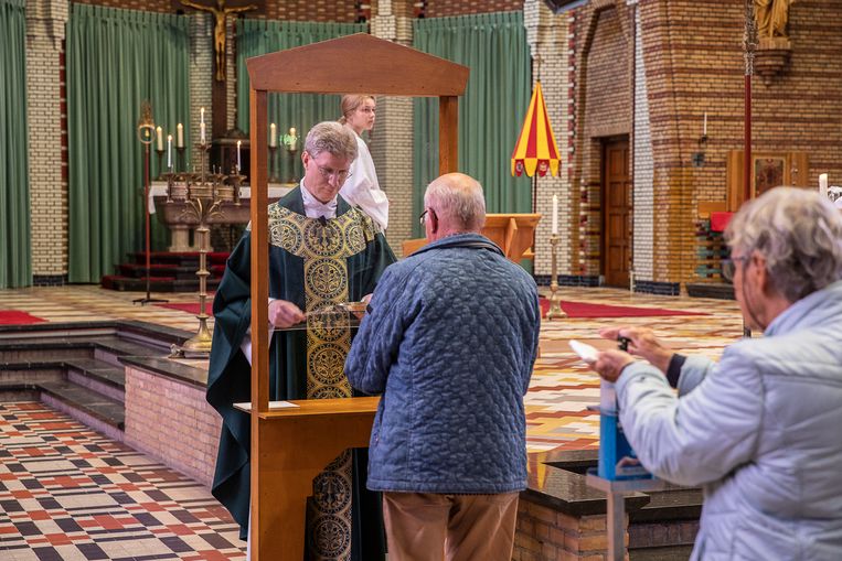 Eerst de desinfectiezeep, daarna een hostie met pincet vanachter een perspex scherm, aangereikt door pastoor Arjen Bultsma van de  de Sint Franciscusbasiliek in Bolsward.  Beeld Harry Cock / de Volkskrant