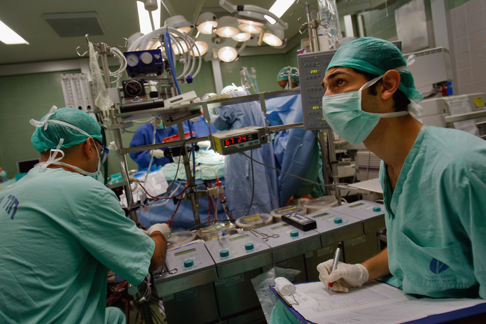 Twee artsen tijdens een vitale hartoperatie. De een houdt op een scherm de lichaamsfuncties in de gaten, de ander bedient de hart-longmachine.